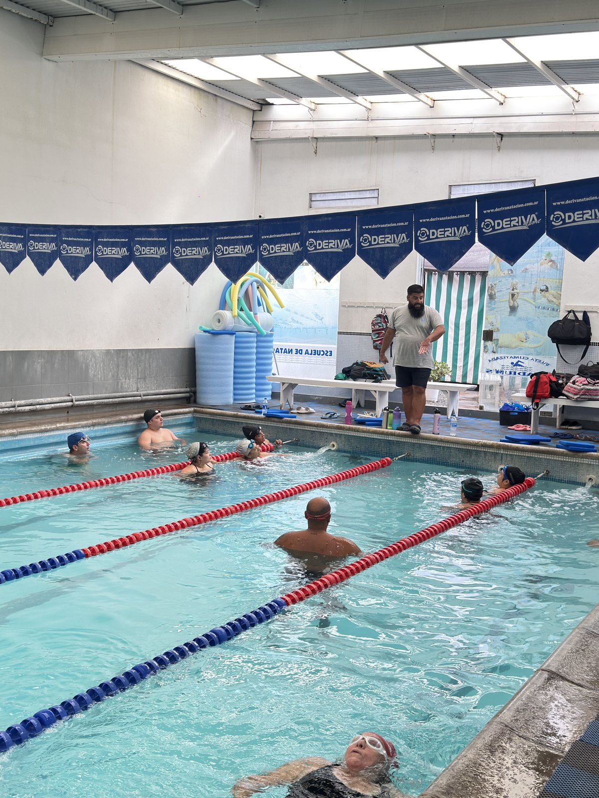 Profesor acompañando la clase de natación desde el borde