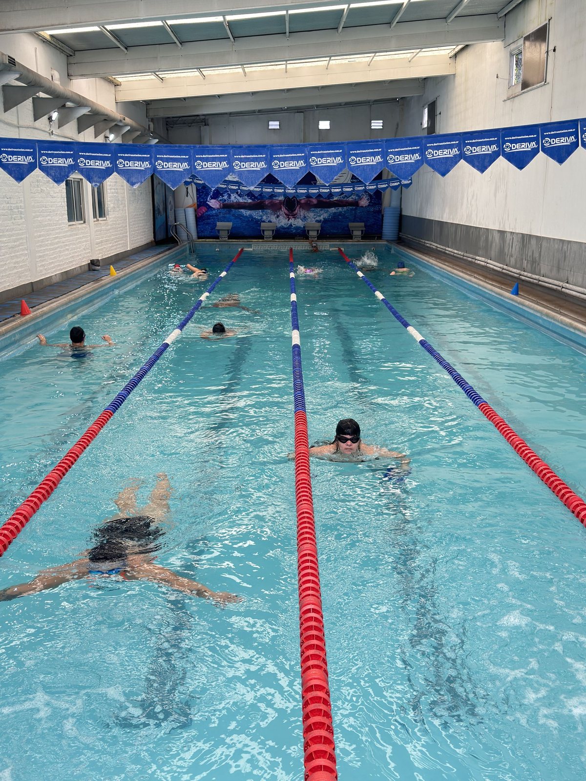 Alumnos nadando por andarivel en la escuela de natación